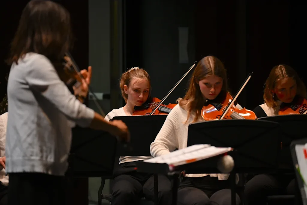 Ms Angela Kost playing violin at concert with studetns