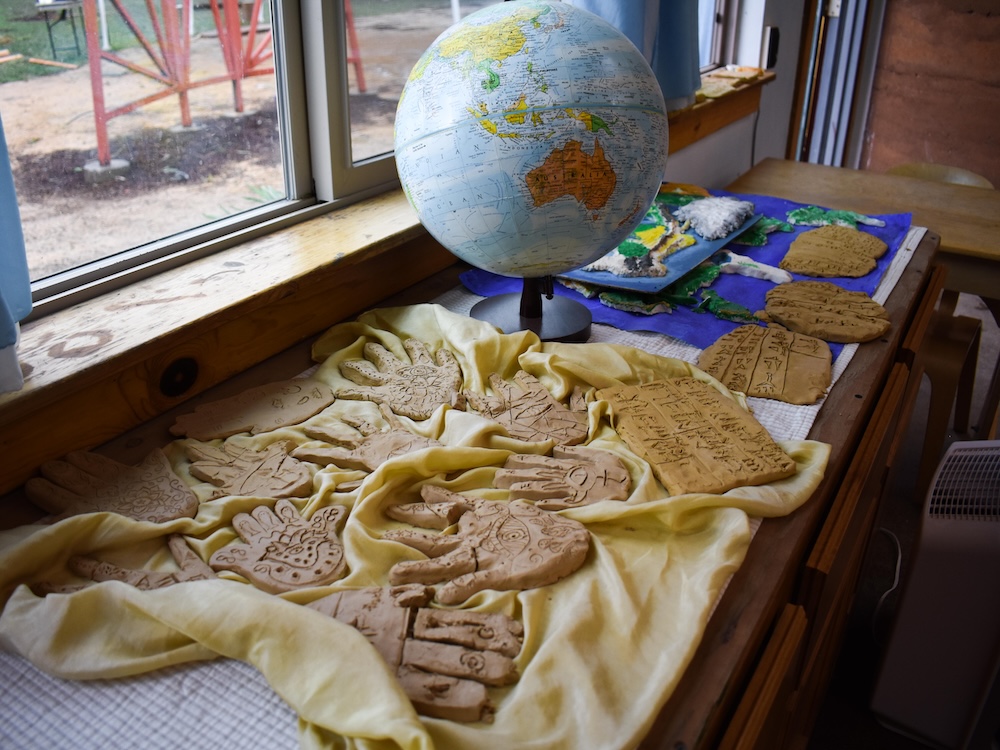 Clay art on shelf next to a globe