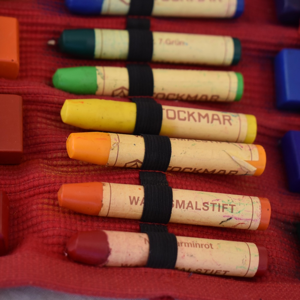 Different color crayons on a red mat