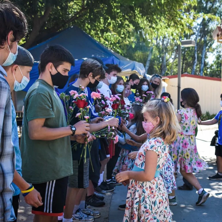 Younger grades presenting flowers to older grades