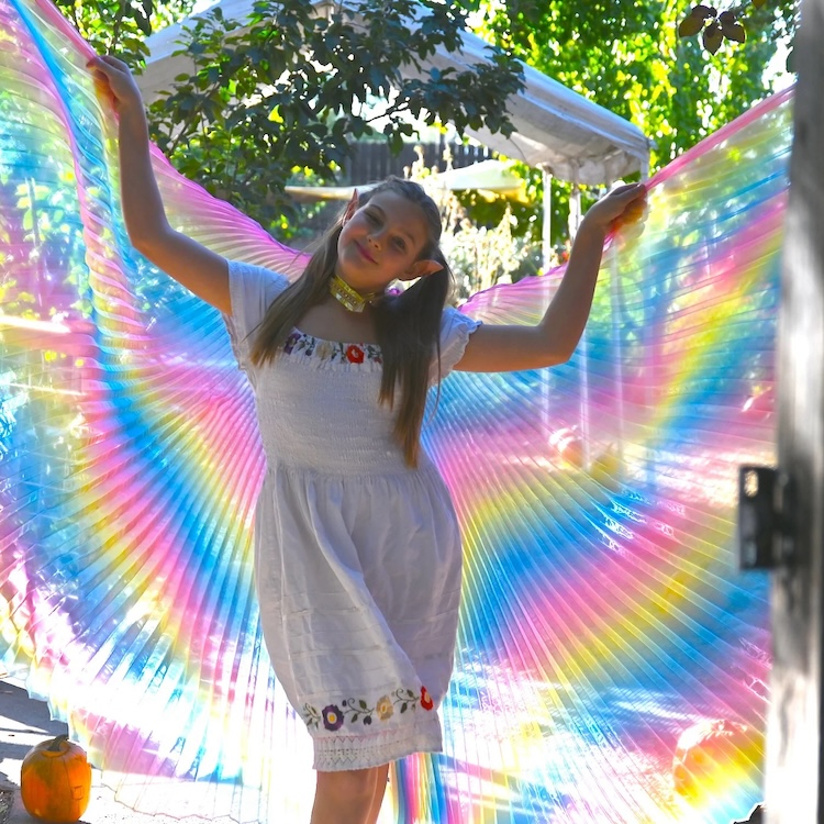 Girl dressed up as a fairy with a colorful cape