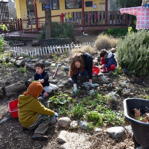 children outside sitting on ground planting