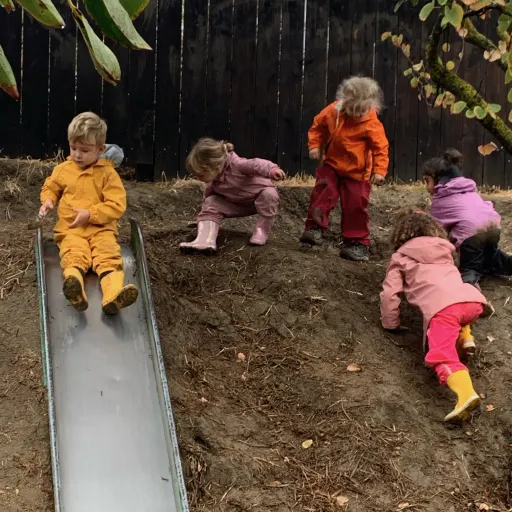 kids in rain gear going down a slide