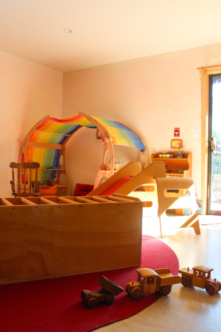 Preschool classroom with toys, rainbow arches, and bountiful natural sunlight.