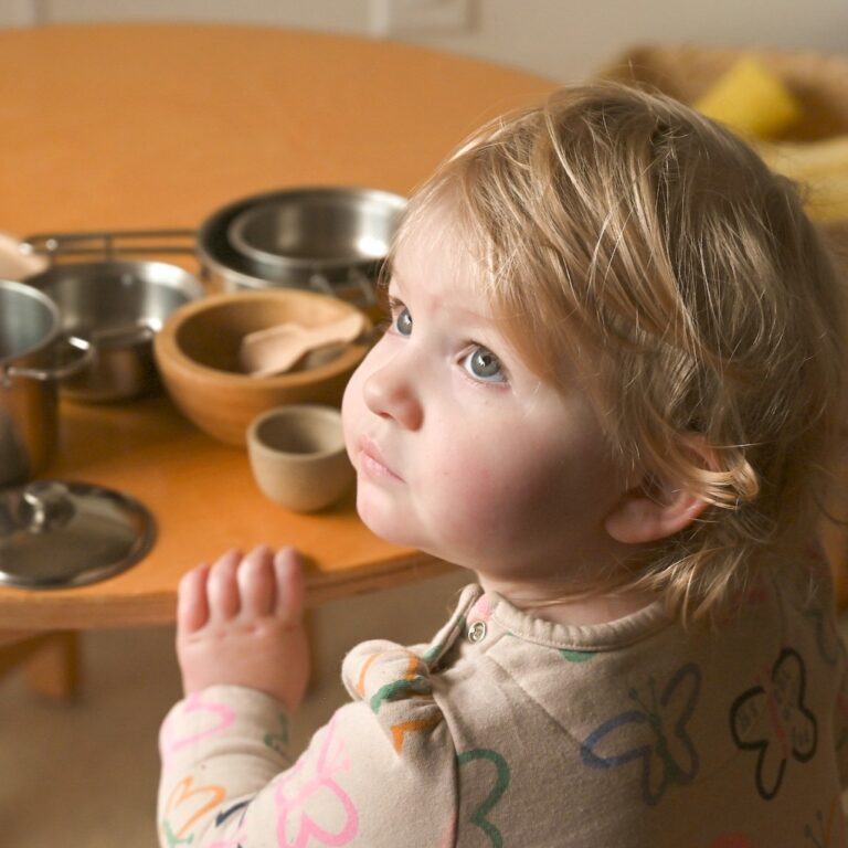 Young child sitting at a table with bowls and utensils