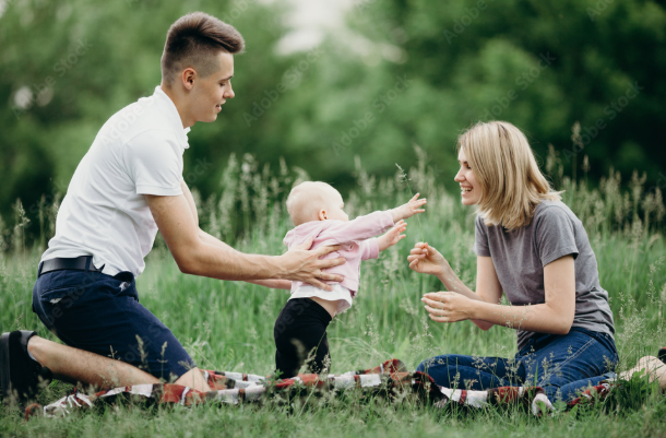 Smiling father, mother and baby on a blanket in a field